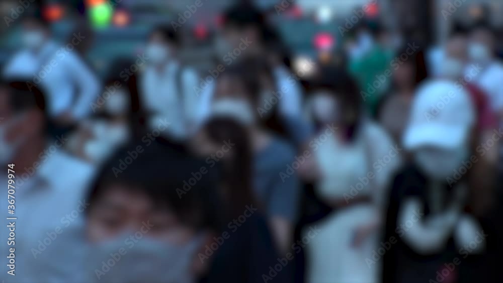 TOKYO, JAPAN - JUL 2020 : Crowd of people at the street near Shinjuku station in rush hour. Commuters wearing surgical mask to protect from Coronavirus (COVID-19) in hot summer. Blurred slow motion.