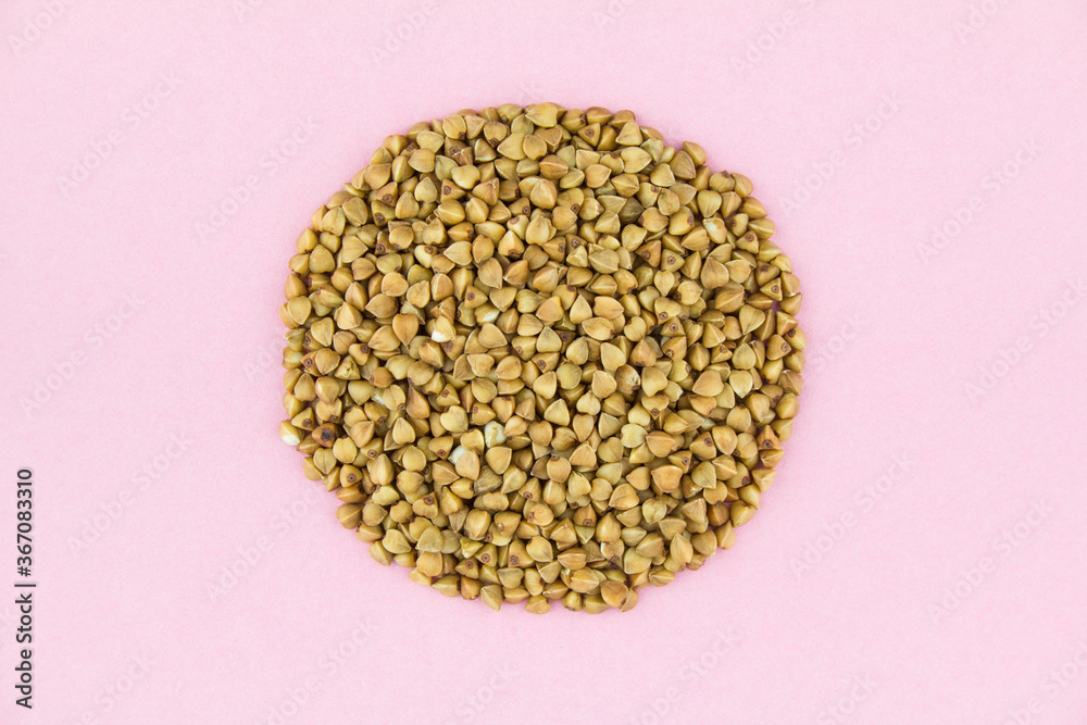 Brown raw buckwheat grains on pink paper background. Brown raw buckwheat grains on pink paper background.