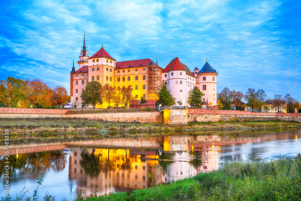 Picturesque morning view of Hartenfels castle on banks of the Elbe. Dramatic sunrise