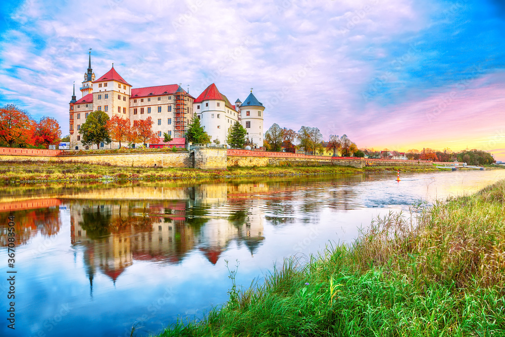 Fantastic morning view of Hartenfels castle on banks of the Elbe. Dramatic sunrise