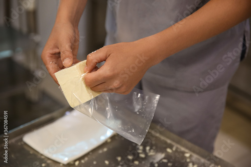 Worker packaging feta cheese at modern factory, closeup