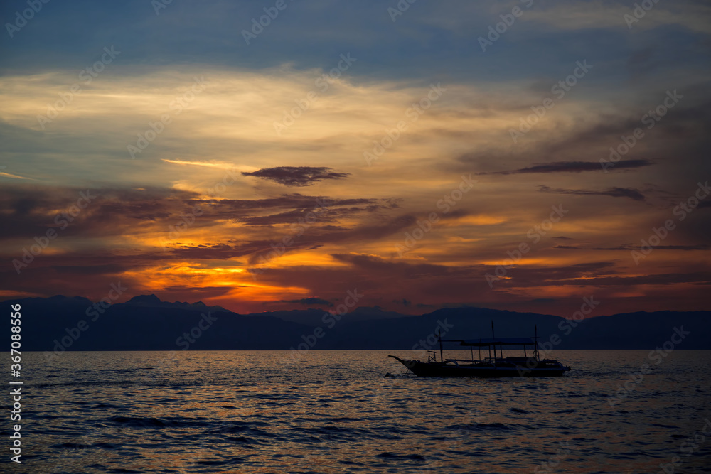 Sunset sea landscape with native boat. Philippines travel photo of beautiful seaside. Early morning seascape sun and cloud. Blue orange scenic sky view. Tropical seaside on sunrise. Summer vacation