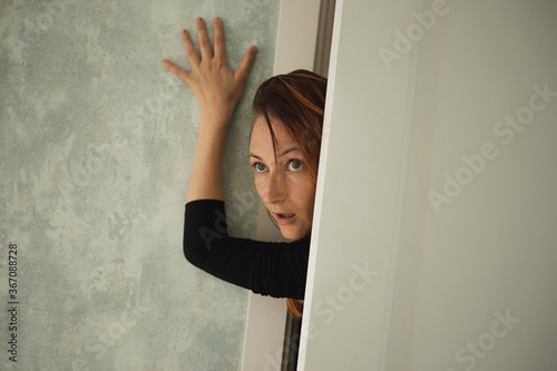 Beautiful woman peeking out from behind the door