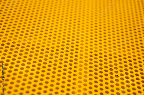 Yellow plate of steel with regular pattern of holes 