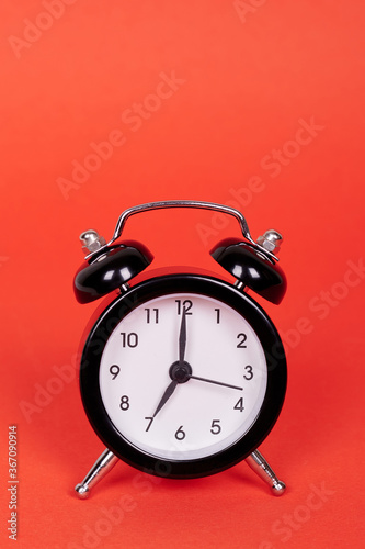 Classic analog clock with bells. Isolated on red background. Copy space.