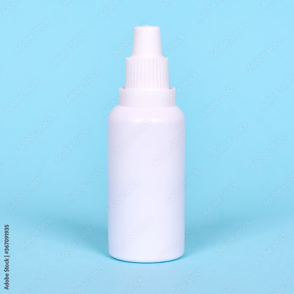 Nasal spray, drops in white bottle. Isolated on blue background. Nasal spray, drops in white bottle. Isolated on blue background.