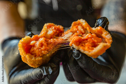 Chef mentre spacca a metà un arancino di riso con sugo di pomodoro photo