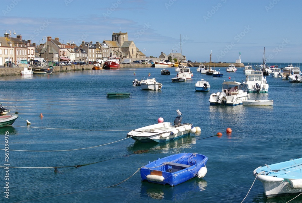 Fishing harbour, boats and terraced seaside cottages on a sunny day in Barfleur, Normandy, France.