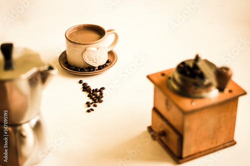 Cup of coffee with milk, coffee milk and mocha teapot on the white table. Warm color tones.