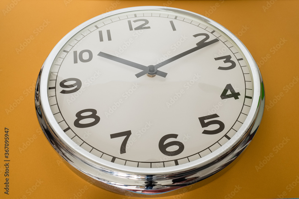 A simple mirrored round watch is taken at a bottom angle against a light brown background. A simple mirrored round watch is taken at a bottom angle against a light brown background.