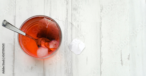 Foto cup of infusion of red berries with ice and spoon on white background