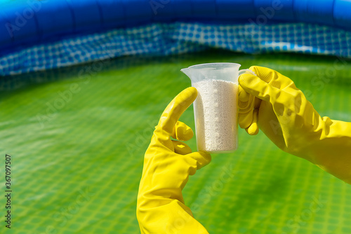 addition of chlorine powder for the pool to remove algae and disinfect water. inflatable swimming pool care concept. photo