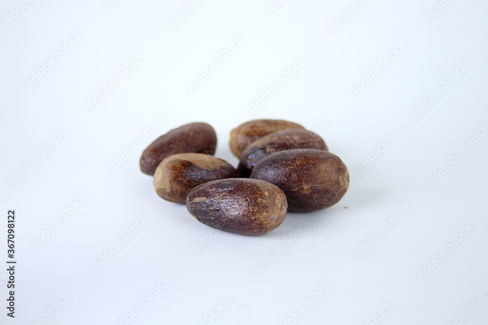 Fototapeta premium Dark brown whole seeds of nutmeg and white background.