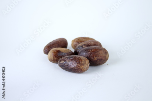Dark brown whole seeds of nutmeg and white background.
