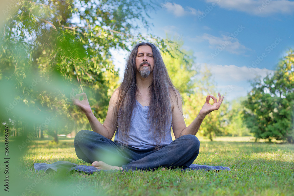 Spiritual man meditating on grass at a city park