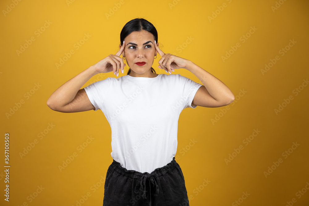 Young beautiful woman standing over isolated yellow background smiling and thinking with her fingers on her head that she has an idea