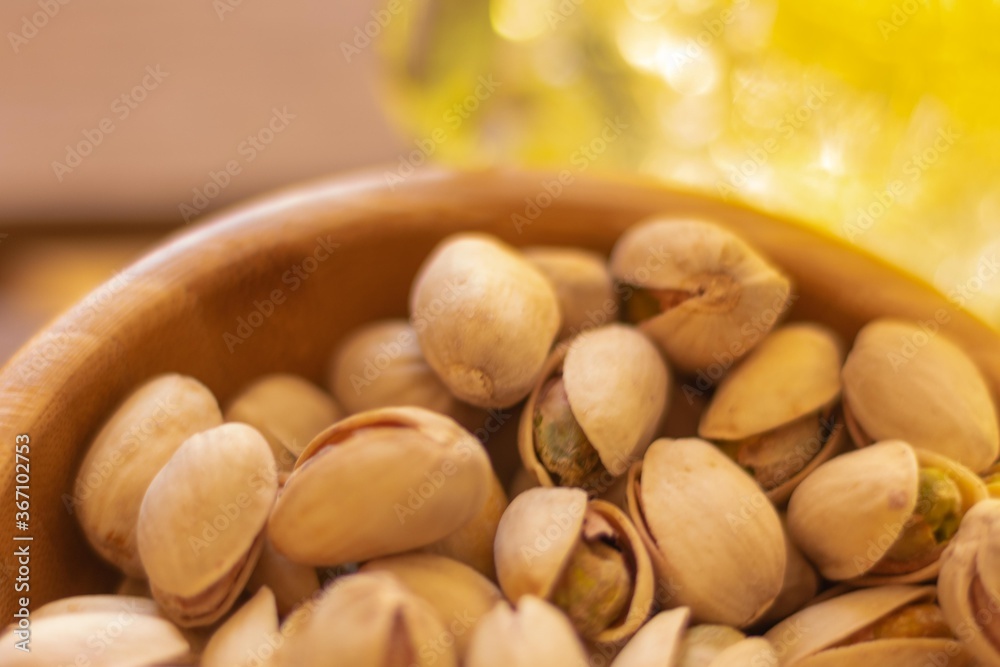 detail of a wooden bowl full of pistachio nuts appetizers on a simple wooden table with a lemonade on a hot day detail of a wooden bowl full of pistachio nuts appetizers on a simple wooden table with a lemonade on a hot day
