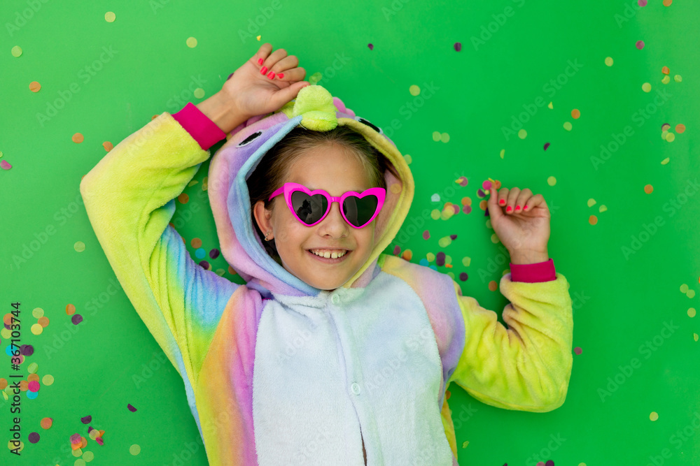 little girls in bright costumes lie on a green isolated background with a streamer in bright unicorn costumes. Space for text. The concept of a holiday, Birthday and sales