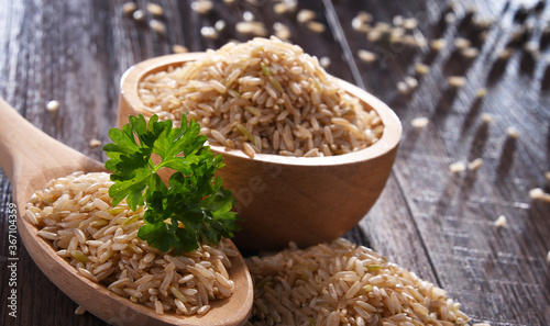 Composition with bowl of brown rice on wooden table