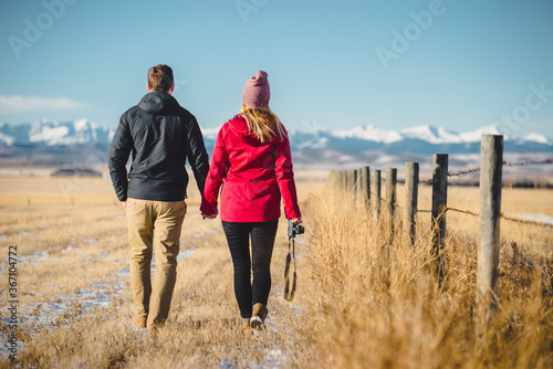 Couple holding hands as the walk through field 