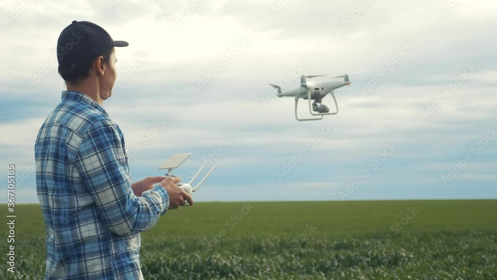 lifestyle smart farming tech agriculture farming. man farmer engineer studies a wheat crop in a green field using a technology quadcopter. male red worker neck works in a green field in a field of lifestyle smart farming tech agriculture farming. man farmer engineer studies a wheat crop in a green field using a technology quadcopter. male red worker neck works in a green field in a field of