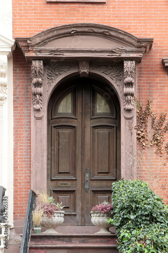 Vintage shabby-looking entry door in New York decorated with arch and corbels. USA.