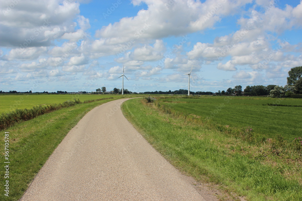 Rural landscape with windmills and country road in the Netherlands. Photo was taken on a beautiful sunny day with and clear blue sky.