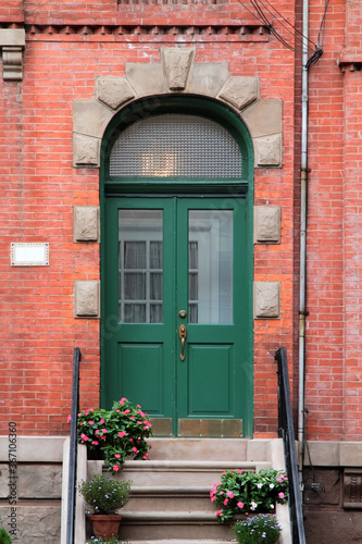 Green vintage shabby-looking double entry door decorated with arch and rustication. New York. USA.