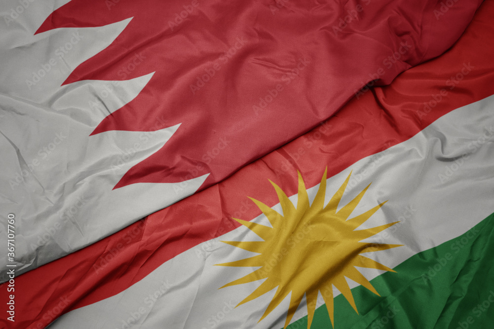 waving colorful flag of kurdistan and national flag of bahrain.