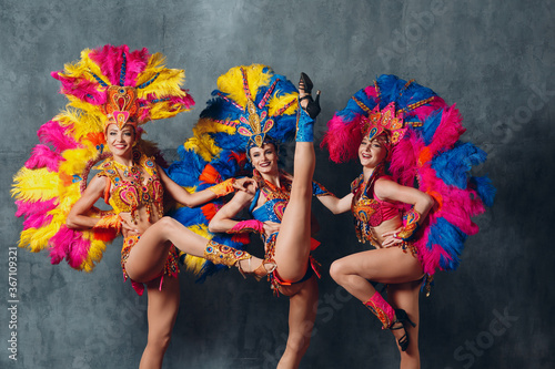Canvas Print Three Women in cabaret costume with colorful feathers plumage.