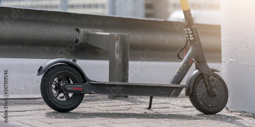 electric scooter with black wheel stands on pavement near road safety steel barrier transport rent concept