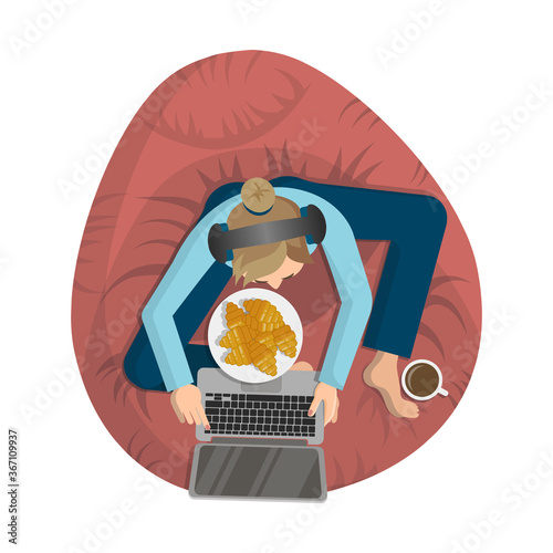 Young woman is sitting in headphones and with laptop on a pink bean bag chair and listening to music
