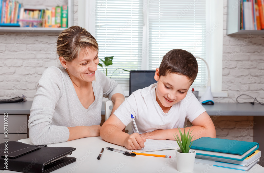 Smiling mother helping her son making homework. Home schooling Smiling mother helping her son making homework. Home schooling