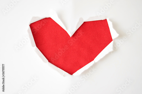 Red paper hole with torn sides in shape of heart on white background for copy space. Greeting card for Valentine`s Day, Women`s Day or Wedding invitation.