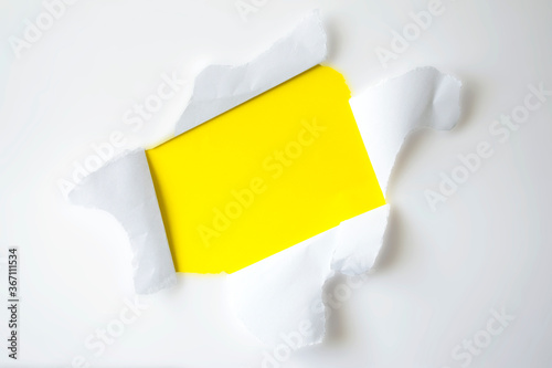 Yellow paper ripped hole in shape of rectangle behind white background for copy space. Through paper.
