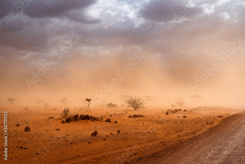 Photo Climate change in Africa: Dirt road and orange dusty sandstorm blowing sand next
