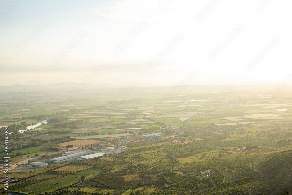 Fototapeta premium Sunlight illuminating a landscape of farmland and a town