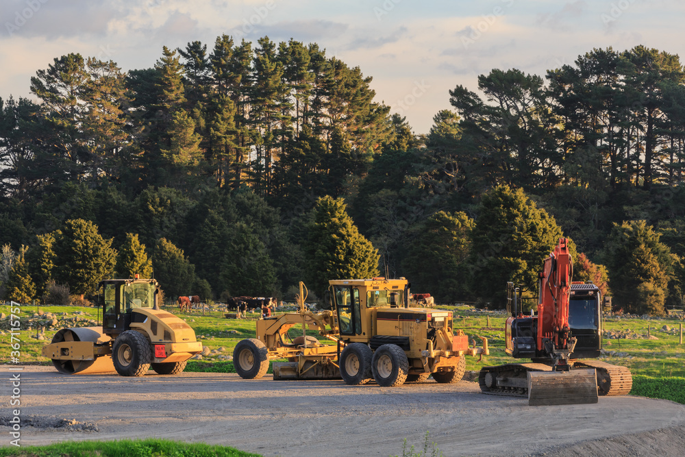 Road-making vehicles in the countryside. From left to right are a road roller, a grader, and a crawler excavator Road-making vehicles in the countryside. From left to right are a road roller, a grader, and a crawler excavator