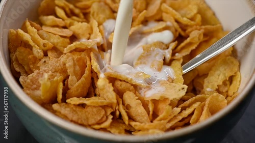 pouring milk into bowl of corn flakes, top view