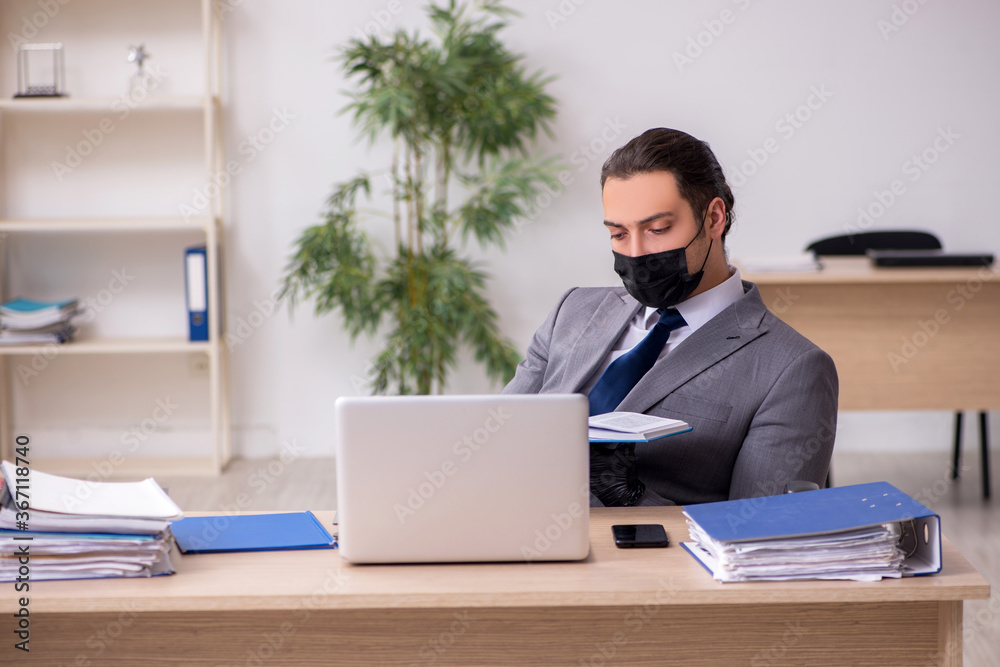 Young male employee in the office during pandemic disease Young male employee in the office during pandemic disease