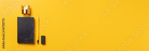 content is king for online marketing concept.top view of black notebook with golden crown ,pencil and eraser on yellow table background.banner template for adding your advertise online