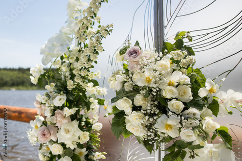 Close up of wedding decor with white transparent screens and fresh white flowers . Wedding exit ceremony with white screens with feather and white rose