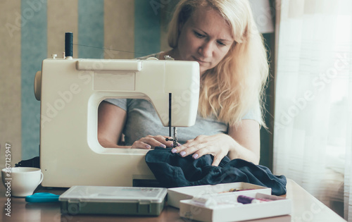 A woman at home works on a sewing machine, a woman at home sews on a sewing machine
