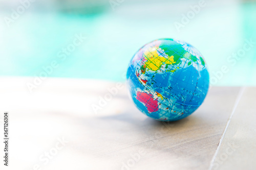 Globe Stress Relief Bouncy Ball over blurred blue water background, world environment, outdoor day light, selective focus