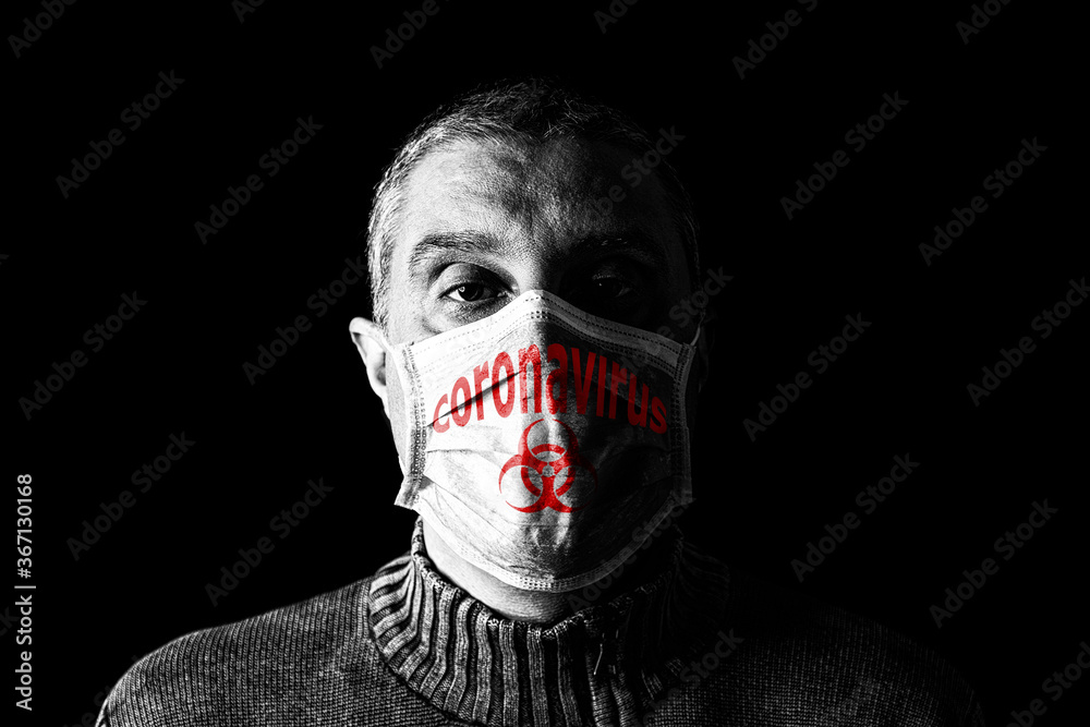 Man with surgical mask. Biohazard and Coronavirus aka COVID-19 symbol. Pandemic or epidemic and scary, fear or danger concept. Black Background