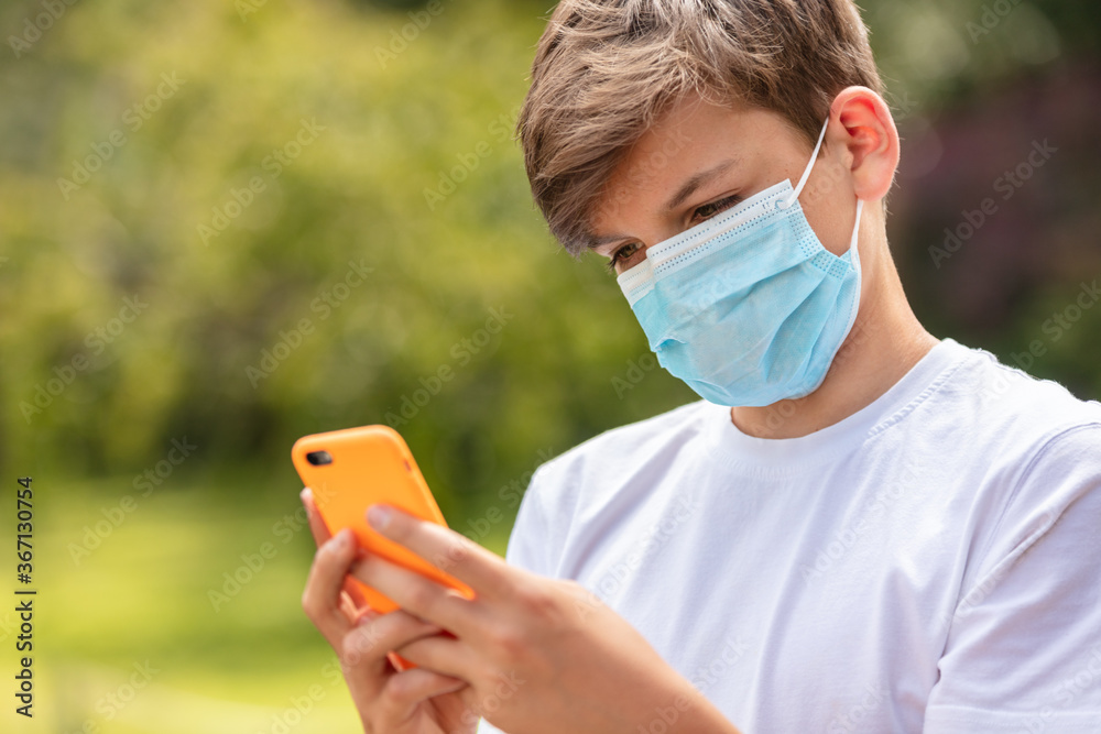 Plakat Chłopiec nastolatek nastolatek dziecko mężczyzna noszący maskę za pomocą telefonu komórkowego Koronawirus COVID-19 Pandemia