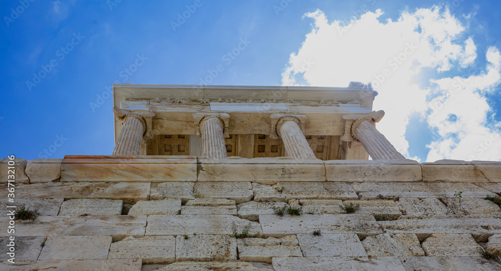 Athens, Greece. Propylaea and Temple of Athena Nike in the Acropolis, monumental gate, blue cloudy sky in spring sunny day.