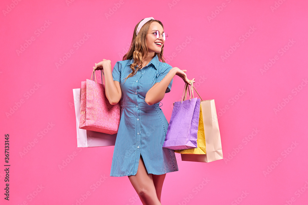 Beautiful woman with a shopping bag. Isolated on pink.