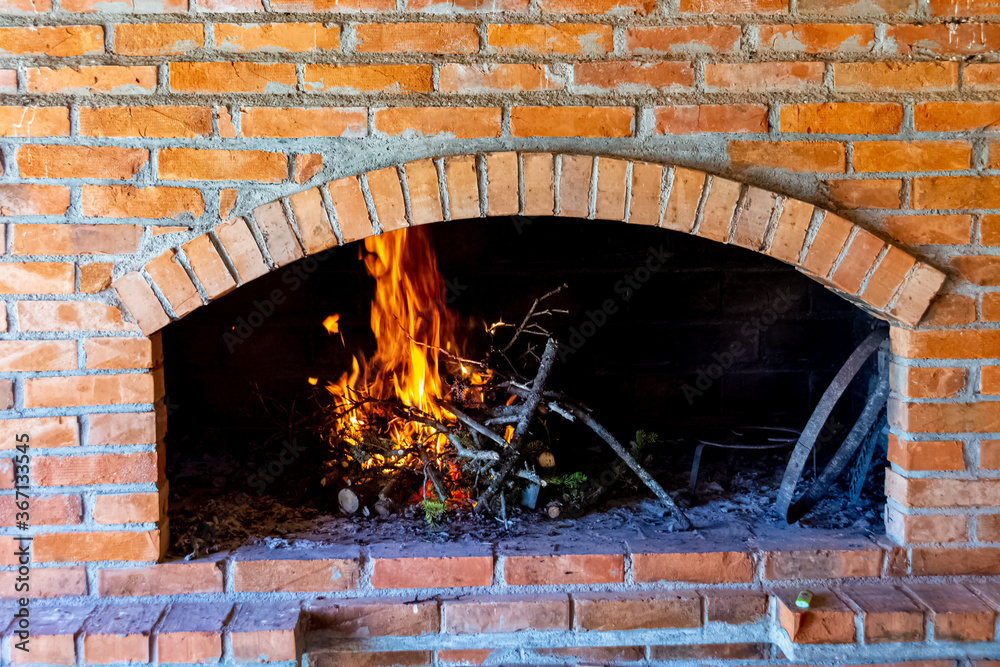 Branches are burning inside fireplace made of bricks for making the food Branches are burning inside fireplace made of bricks for making the food