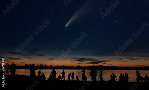 Comet Neowise comet C/2020 F3 (NEOWISE) and crowd of people silhouetted by the Ottawa river watching and photographing the comet